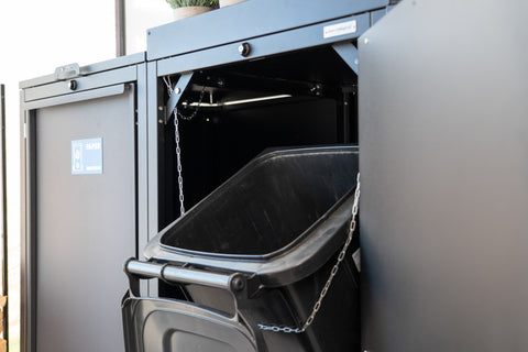 Bio Stefan Mülltonnenbox mit geöffneter Tür und schwarzer Mülltonne im Inneren.