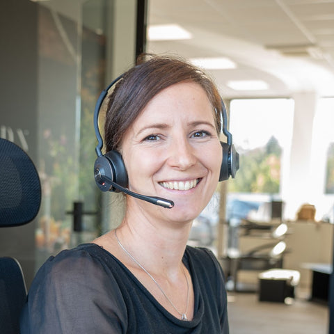 Lächelnde Frau mit Headset in einem Büro von Bio Stefan.