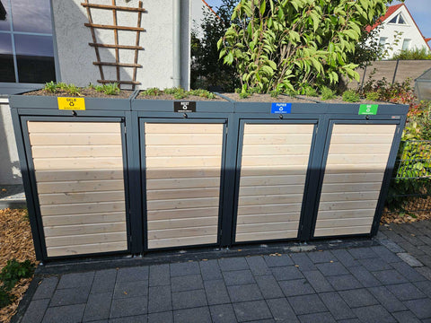 Kundenfoto: BIO Stefan Mülltonnenbox Holzmichl in Anthrazit mit Holzfront und Pflanzdach, die vier Fächer sind mit Gelb, Rest, Papier und Bio beschriftet