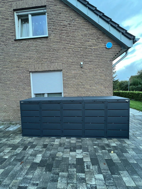 Black 4-bin garbage can box from BIO Stefan in front of a brick house.