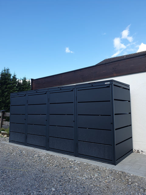 Schwarze BIO Stefan Mülltonnenbox 4er vor strahlend blauem Himmel.