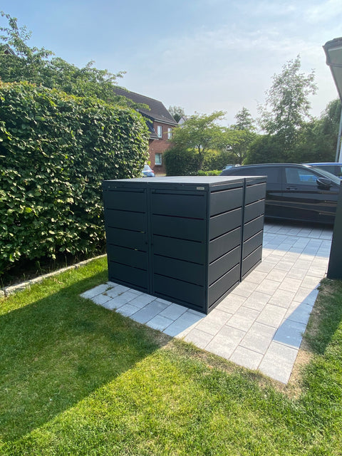 Black BIO Stefan 4-bin garbage can box on paved ground in the garden.