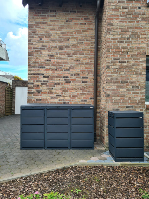 Black garbage can boxes from BIO Stefan next to a brick building.