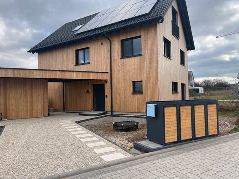 Maison en bois avec BIO Stefan Coffre à poubelles 4 places devant l'entrée.