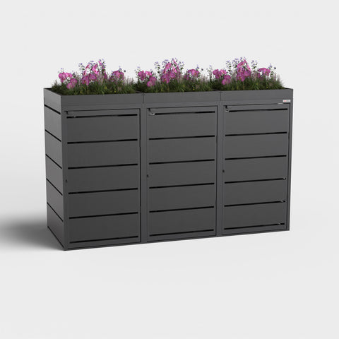 Dagobert 3er Mülltonnenbox 240L RAL9005 mit Pflanzdach und lila Blumen.