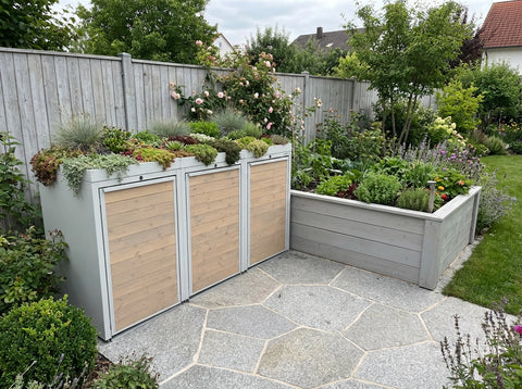 BIO Stefan Mülltonnenbox mit Pflanzdach neben großem Hochbeet im gepflegten Garten