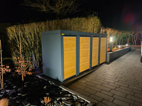 Holzmichl Mülltonnenbox bei Nacht im Garten mit Beleuchtung.