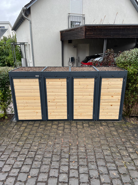 Mülltonnenboxen aus Holz und Metall vor einem Wohnhaus.