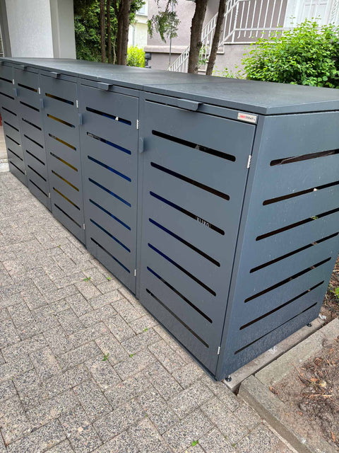 BIO Stefan Alubert Mülltonnenbox 5er 240l in Anthrazit seitlich auf gepflastertem Weg vor Hecke