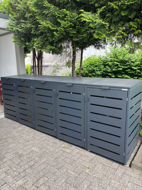 BIO Stefan Alubert Mülltonnenbox 5er 240l in Anthrazit frontal auf Pflaster vor Koniferen