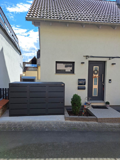 BIO Stefan Dagobert Mülltonnenbox 3er 240l in Anthrazit mit Deckel frontal vor der Hausfassade zwischen Nebengebäude und Haustür