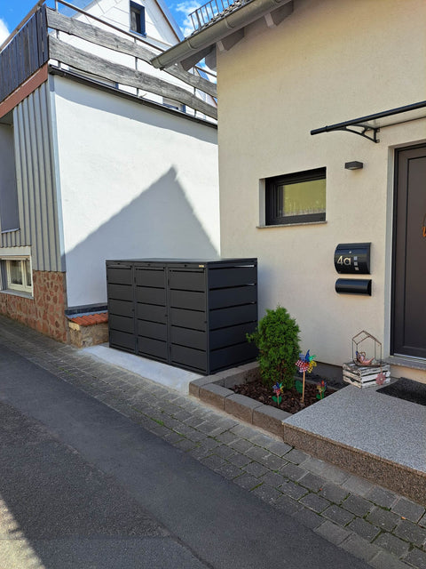 BIO Stefan Dagobert Mülltonnenbox 3er 240l in Anthrazit mit Deckel von der Gasse aus gesehen, Betonstreifen am Pflasterrand vor dem Haus