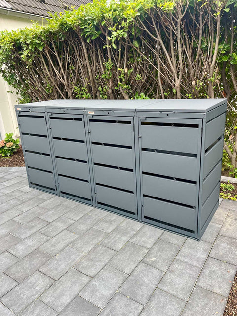 BIO Stefan Dagobert Mülltonnenbox 4er 120l in Anthrazit steht auf grauen Pflastersteinen vor Hecke