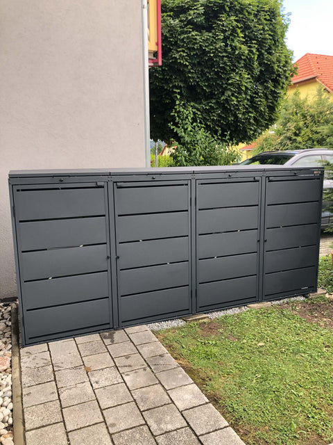 BIO Stefan Mülltonnenbox Dagobert 4er 240l in Anthrazit steht längs an Hauswand neben Rasen und Pflasterweg