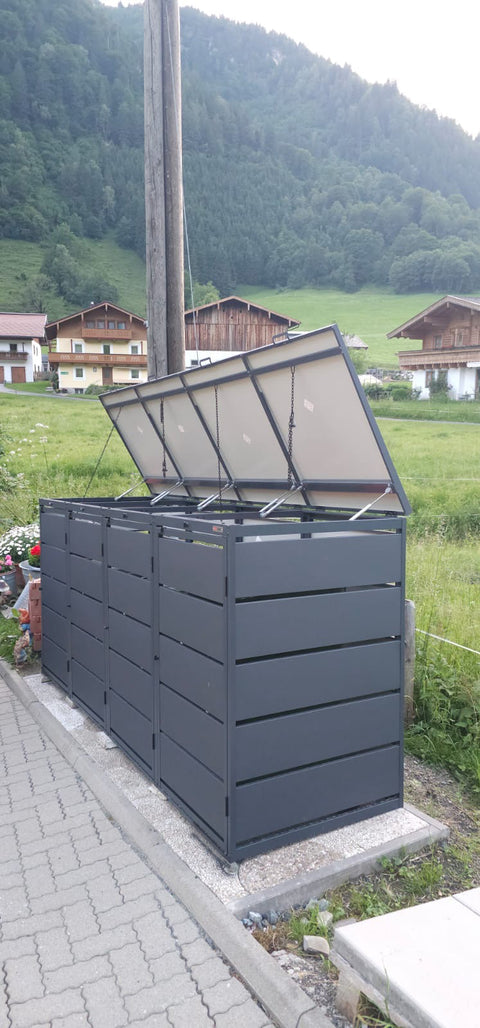 BIO Stefan Dagobert Mülltonnenbox 4er 240l in Anthrazit mit geöffneten Deckeln vor Häusern im Grünen