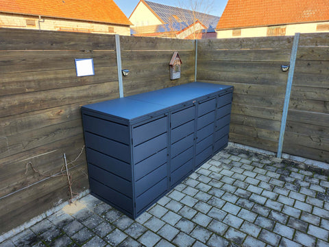 BIO Stefan Dagobert Mülltonnenbox 4er 240l in Anthrazit steht an Holzzaun auf gepflastertem Hof