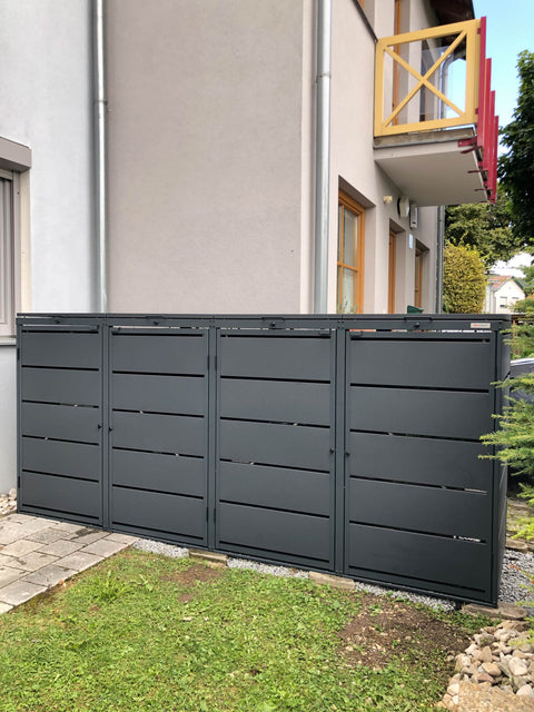 BIO Stefan Dagobert Mülltonnenbox 4er 240l in Anthrazit vor Mehrfamilienhaus auf Rasenfläche