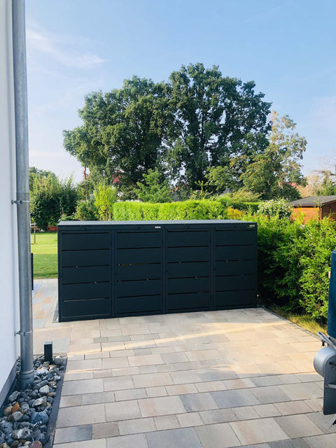 BIO Stefan Dagobert Mülltonnenbox 4er 240l in Anthrazit auf gepflasterter Terrasse vor Gartenhecke