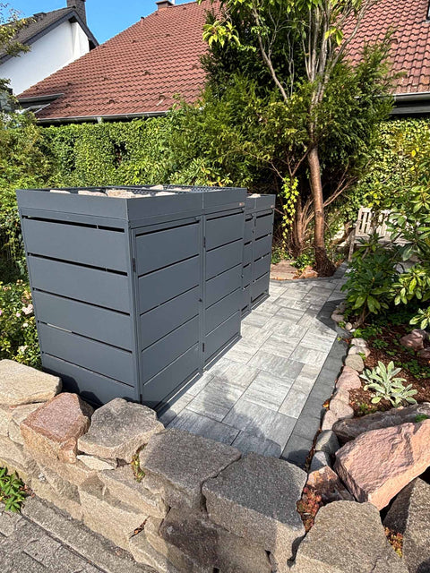 BIO Stefan Dagobert Mülltonnenbox 4er Kombination 120l und 240l in Anthrazit mit Pflanzdach, entlang des Gartenwegs aufgestellt mit Natursteineinfassung