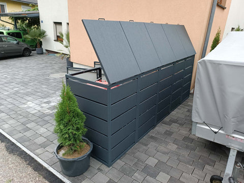 BIO Stefan Dagobert Mülltonnenbox 5er 240l in Anthrazit mit geöffneten Klappdeckeln in seitlicher Ansicht neben der Einfahrt
