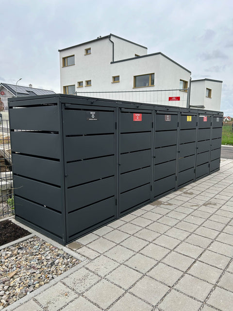 BIO Stefan Dagobert Mülltonnenbox 6er 240l in Anthrazit mit Klappdeckel in einer Neubausiedlung, Fächer beschriftet mit Rest, Papier, Bio und Gelb, auf Betonplatten mit Splittfugen