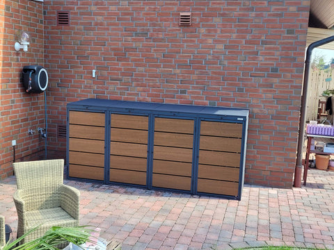 BIO Stefan Dagobert Mülltonnenbox 4er 240l in Anthrazit mit Holzoptik-Front an Ziegelhauswand