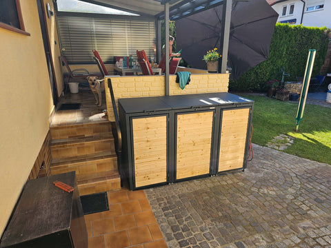 BIO Stefan Holzmichl Mülltonnenbox 3er 120l und 240l in Anthrazit auf Natursteinpflaster neben der überdachten Terrasse