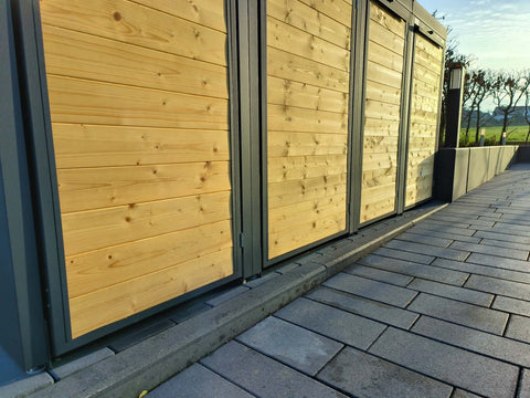 BIO Stefan Mülltonnenbox Holzmichl Anthrazit, Holzfront 4er 120l mit Pflanzdach auf gepflasterter Terrasse