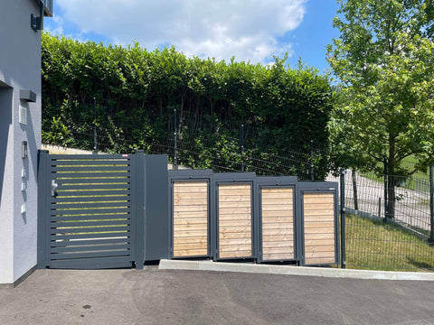 BIO Stefan Holzmichl Mülltonnenbox 4er 120l in Anthrazit mit Holzfront vor Haus, auf Schräge platziert