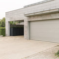 Stahlfred Waste garbage can box next to modern garage with gray tiles.