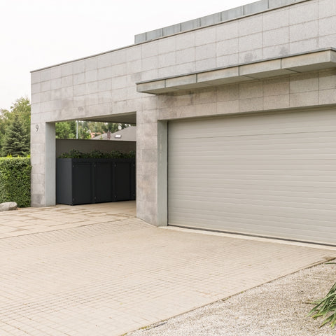 Stahlfred Mülltonnenbox neben moderner Garage mit grauen Fliesen.