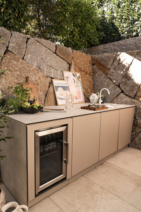 BIO Stefan Outdoorküche mit integriertem Kühlschrank vor einer Natursteinmauer