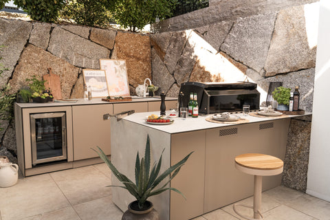 BIO Stefan Outdoorküche mit Kühlschrank und Einbaugrill vor einer Natursteinmauer
