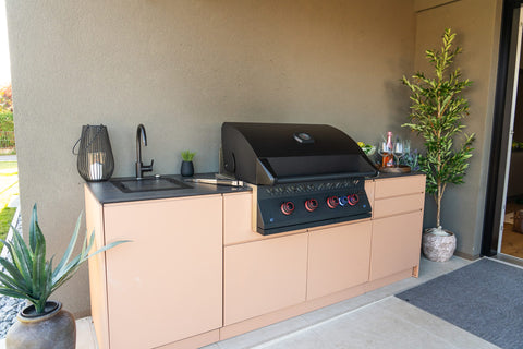 Outdoor kitchen against the house wall under the canopy: sink, Napoleon Phantom, and drawers in one row