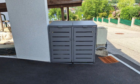 BIO Stefan Alubert Mülltonnenbox 2er 240l in Graualuminium geschlossen auf der asphaltierten Zufahrt im leichten Gefälle an der Hausecke