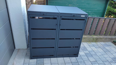 BIO Stefan Dagobert Muelltonnenbox 2er 120l in Anthrazit an der Garagenwand auf gepflasterter Terrasse vor Holzzaun