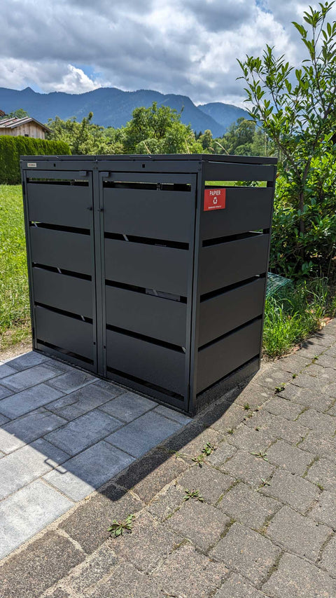 BIO Stefan Dagobert Muelltonnenbox 2er 120l in Anthrazit freistehend am Gartenrand vor Thujenhecke auf Plattenfundament mit Bergpanorama