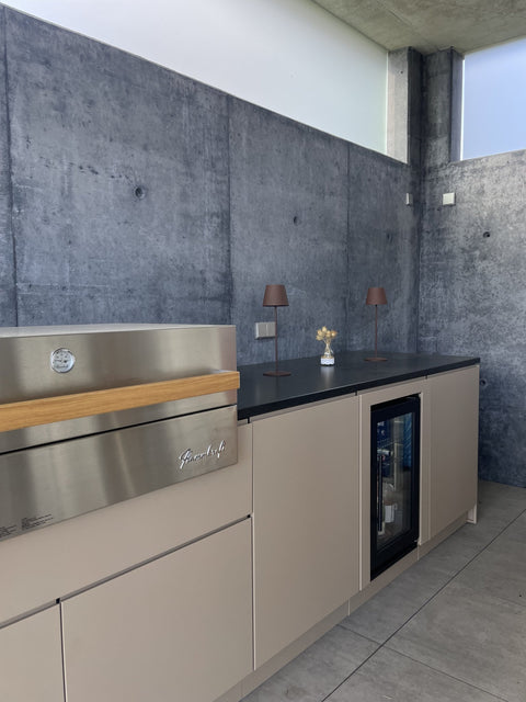 Outdoor kitchen by the pool with Flammkraft grill: front in gray-beige beneath the concrete roof