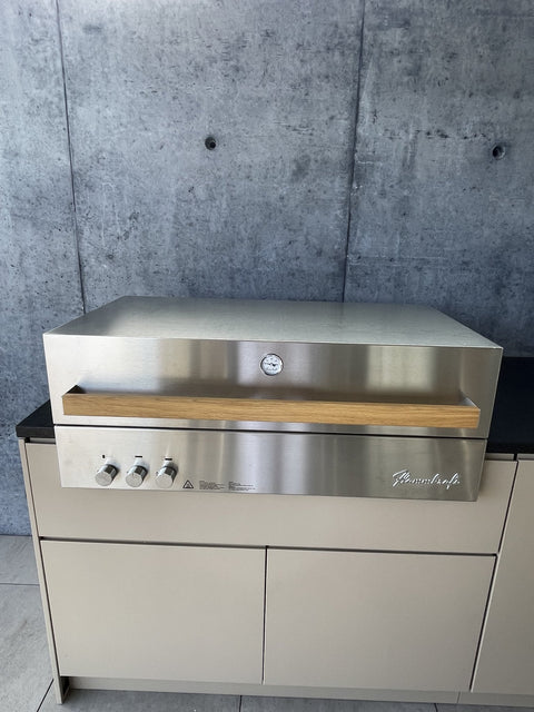 Outdoor kitchen by the pool with Flammkraft grill: front in gray-beige beneath the concrete roof
