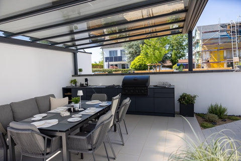 Outdoor kitchen along the garden wall: long kitchen unit in anthracite beside the dining area