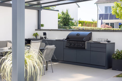 Outdoor kitchen along the garden wall: long kitchen unit in anthracite beside the dining area