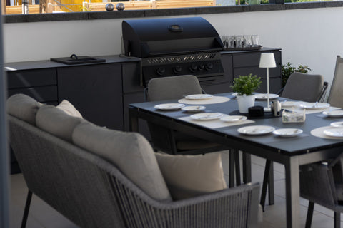 Outdoor kitchen along the garden wall: long kitchen unit in anthracite beside the dining area
