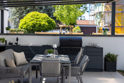 Outdoor kitchen along the garden wall: long kitchen unit in anthracite beside the dining area