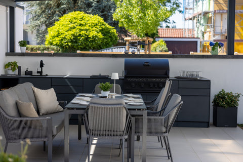 Outdoor kitchen along the garden wall: long kitchen unit in anthracite beside the dining area