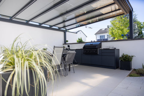 Outdoor kitchen along the garden wall: long kitchen unit in anthracite beside the dining area