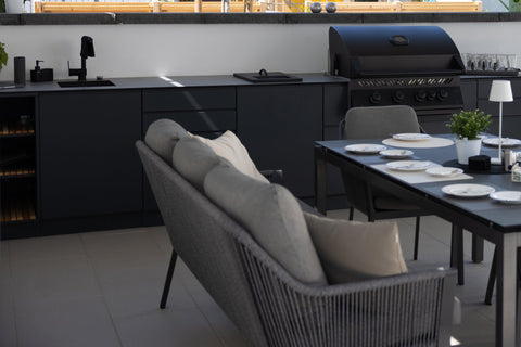 Outdoor kitchen along the garden wall: long kitchen unit in anthracite beside the dining area