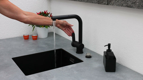 Outdoor kitchen along the garden wall: long kitchen unit in anthracite beside the dining area