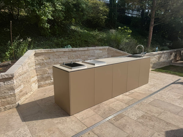 Outdoorküche mit Spüle und Kochfeldern vor Natursteinmauer (Kundenfoto 1)